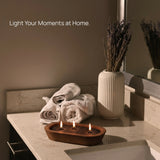Tula black candle sand glowing in a wooden bowl on a bathroom vanity with rolled towels and dried lavender.