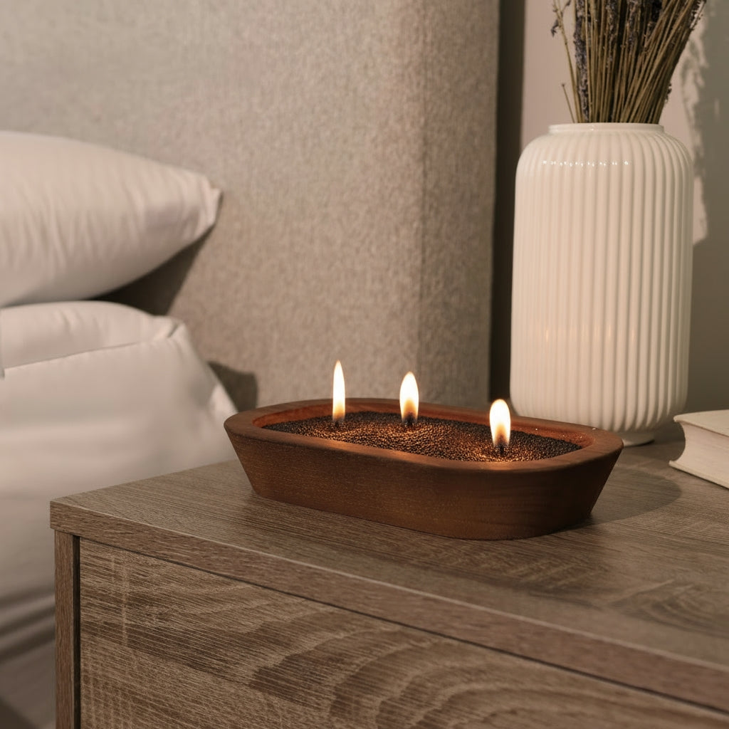 Refillable candles. Tula black candle sand displayed in a dark wooden bowl on a bedside nightstand, with a white ribbed vase and neutral decor in the background. Ideal for relaxation, bedtime rituals, and mindful moments.